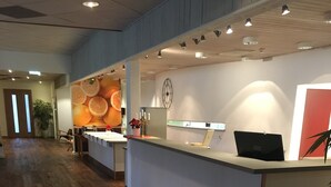 A reception area with a wooden floor, a reception desk, a clock, and a wall with a fruit-themed mural.