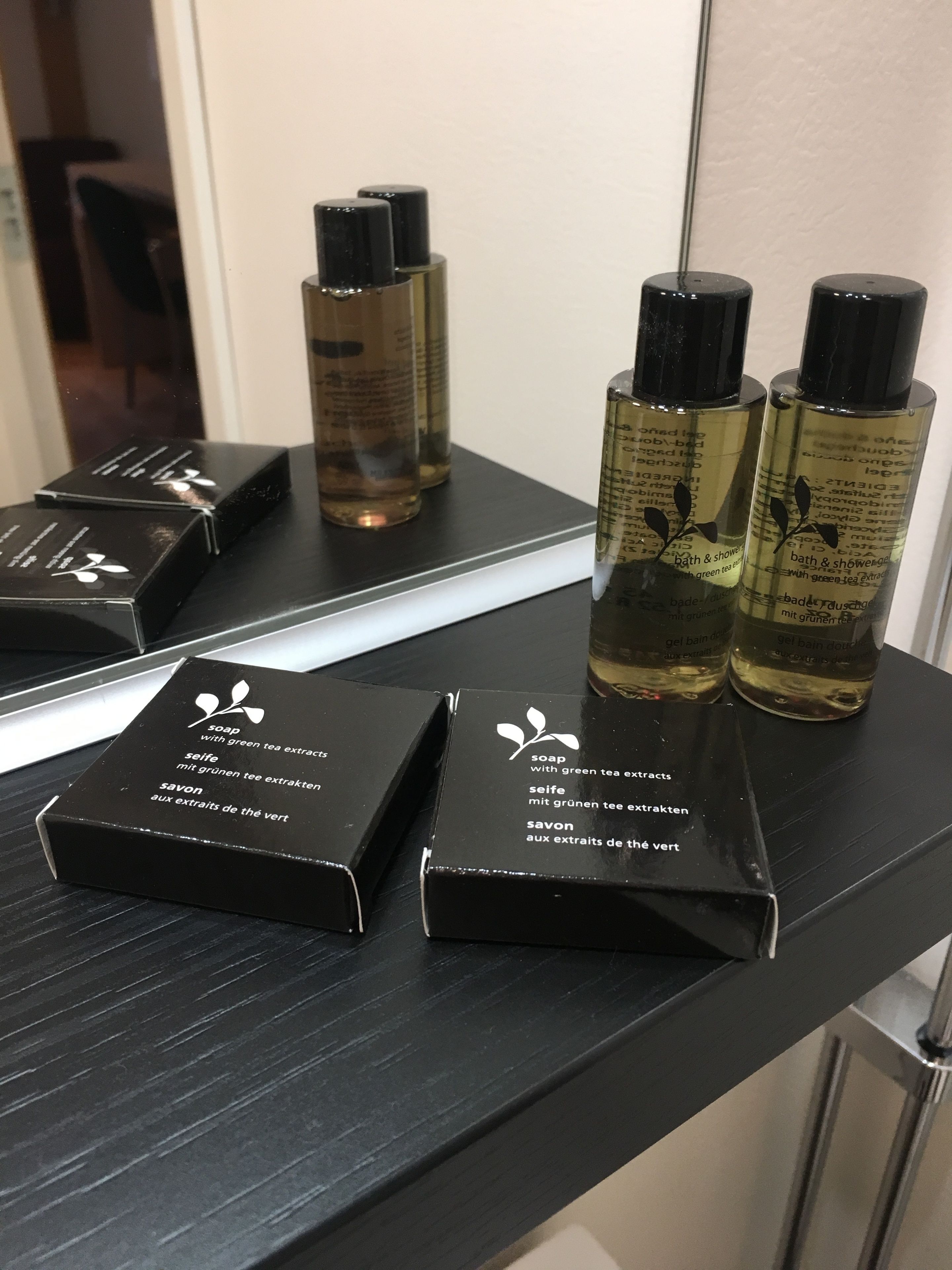 Ein Badezimmer-Schrank mit schwarzen Seifenschachteln und Flaschen mit Grüner Tee Extrakt Seife.