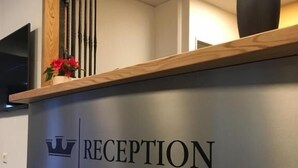 A reception desk with a wooden top, a vase with flowers, and a crown symbol above the word "RECEPTION".