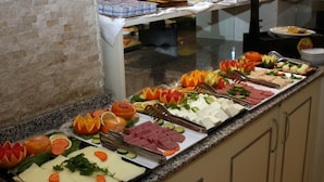 Buffet com diversos alimentos, incluindo frutas, legumes e carnes.