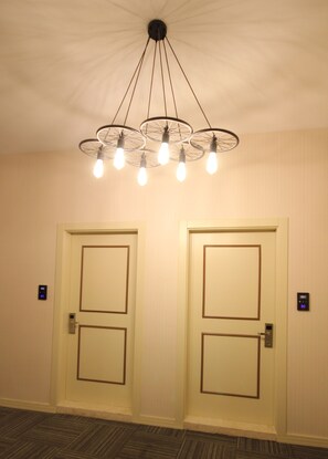 A hallway with two doors, a ceiling light fixture, and a floor with a herringbone pattern. - Ankara Gold Hotel (Ankara)