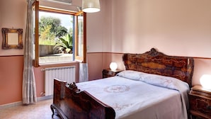 Une chambre avec un lit en bois, une fenêtre avec des rideaux, un radiateur et une lampe de chevet.