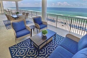 A balcony with wicker furniture, a blue sofa, and a view of the beach and ocean.