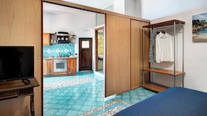 A room with a bed, a TV, a wardrobe, a kitchen area, and a bathroom. - Campanella's Studios (Massa Lubrense)