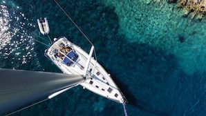 A white yacht with a cabin and deck seating, anchored in clear blue waters with rocky formations nearby. - Campanella's Studios (Massa Lubrense)