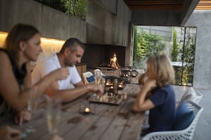 A group of people seated at an outdoor dining table with a fire feature in the background. - Opatija Hills Ika - Luxury Apartments (Opatija)
