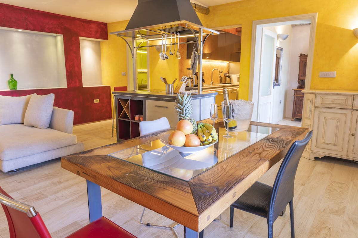 A modern kitchen with a wooden dining table, a built-in stove, and a kitchen island with a bowl of fruit.