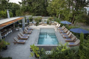 Alberca al aire libre, alberca con cascada y sombrillas en la alberca