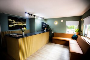 Welcome to our reception area, where guests can relax on a sofa and bench amidst a clean, minimalist design.