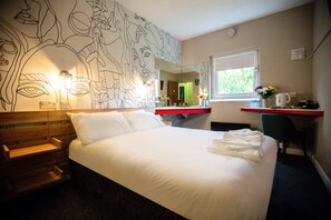 Relax in a spacious room with a large bed, bench, and desk area.
