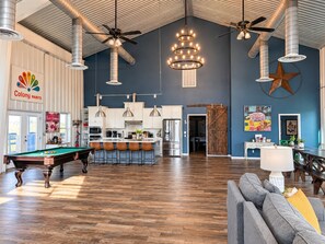 A spacious living area with a pool table, a bar area, and a kitchen in the background. -  Barndo -7 acres- sleeps 28! Great for groups, custom fire pit area, pool table! (Brenham)