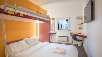 A bunk bed room with a desk, a chair, and a TV.