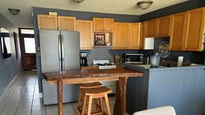A kitchen with wooden cabinets, a stainless steel refrigerator, a microwave, and a coffee maker. - Updated unit, modern and clean (Kihei)