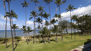 A tropical resort with palm trees, a pool area, and a view of the ocean. - Updated unit, modern and clean (Kihei)