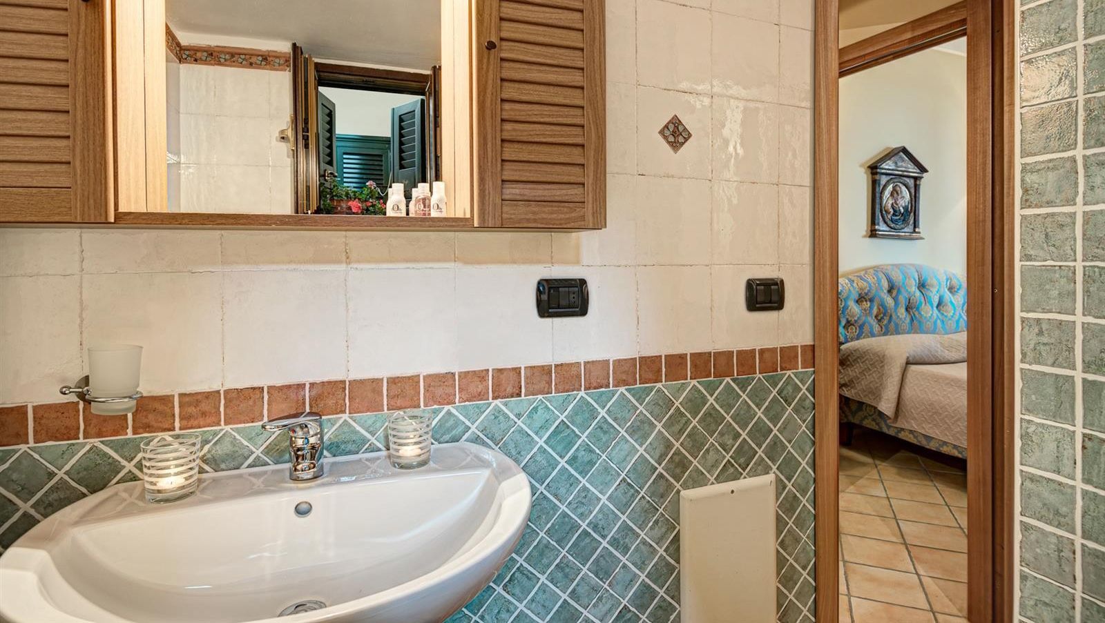 A bathroom with a sink, mirror, and tiled walls.