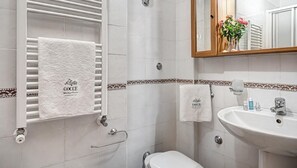 A bathroom with white tiled walls, a white sink, and two towels hanging on towel racks. - Casa Sophia (Massa Lubrense)