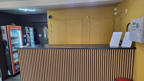 Ein Empfangstresen mit Holzlamellen-Design, ein Automaten und ein Mülleimer.