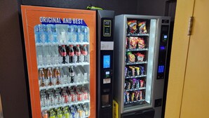 Ein Getränkeautomat mit Coca-Cola Logo und einem Schild mit der Aufschrift 'Original und Beste'.