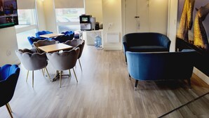 Ein modernes Interieur mit Essbereich, einem blauen Sofa und einem Fernseher.