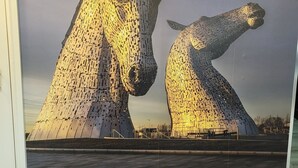 A large, illuminated sculpture of two horses.