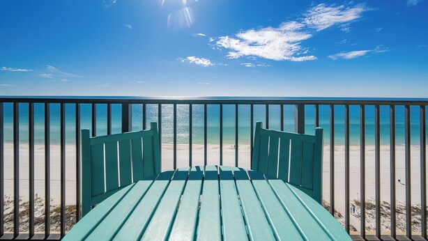 A view from a balcony overlooking a beach with a clear sky.