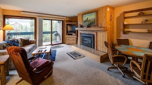 A cozy living room with a fireplace, a dining table, and a sofa.