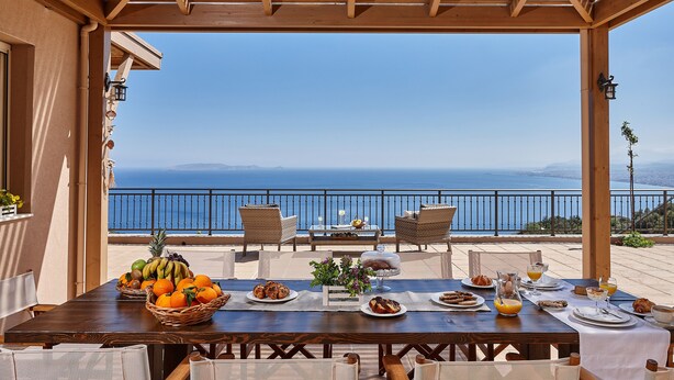 A wooden pergola with a table set for breakfast overlooking a scenic ocean view. - Villa Omikron (Malevizi)