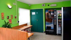 Una stanza con una parete verde, una scrivania in legno, una macchina per distributore e una porta con il logo di Facebook.