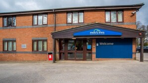 Un hotel Metro Inns con facciata in mattoni, ingresso blu e un cartello con la scritta 'Welcome'.