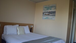 A hotel room with a neatly made bed, a wooden headboard, and a painting on the wall. - Metro Inn Walsall (Walsall)