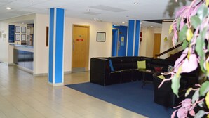A reception area with a reception desk, a black sofa, and a staircase. - Metro Inn Walsall (Walsall)