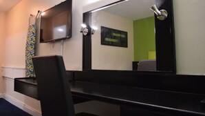 A hotel room with a black desk, a flat-screen TV mounted on the wall, a large mirror, and a patterned curtain. - Metro Inn Walsall (Walsall)