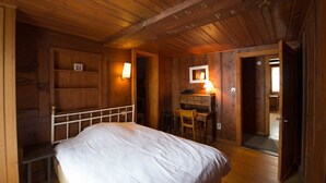 Ein Zimmer in einer Holzhütte mit einem Bett, einem Schreibtisch und einem Stuhl.