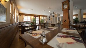 Ein Restaurant mit Holztischen, Stühlen und einer großen Wanduhr.