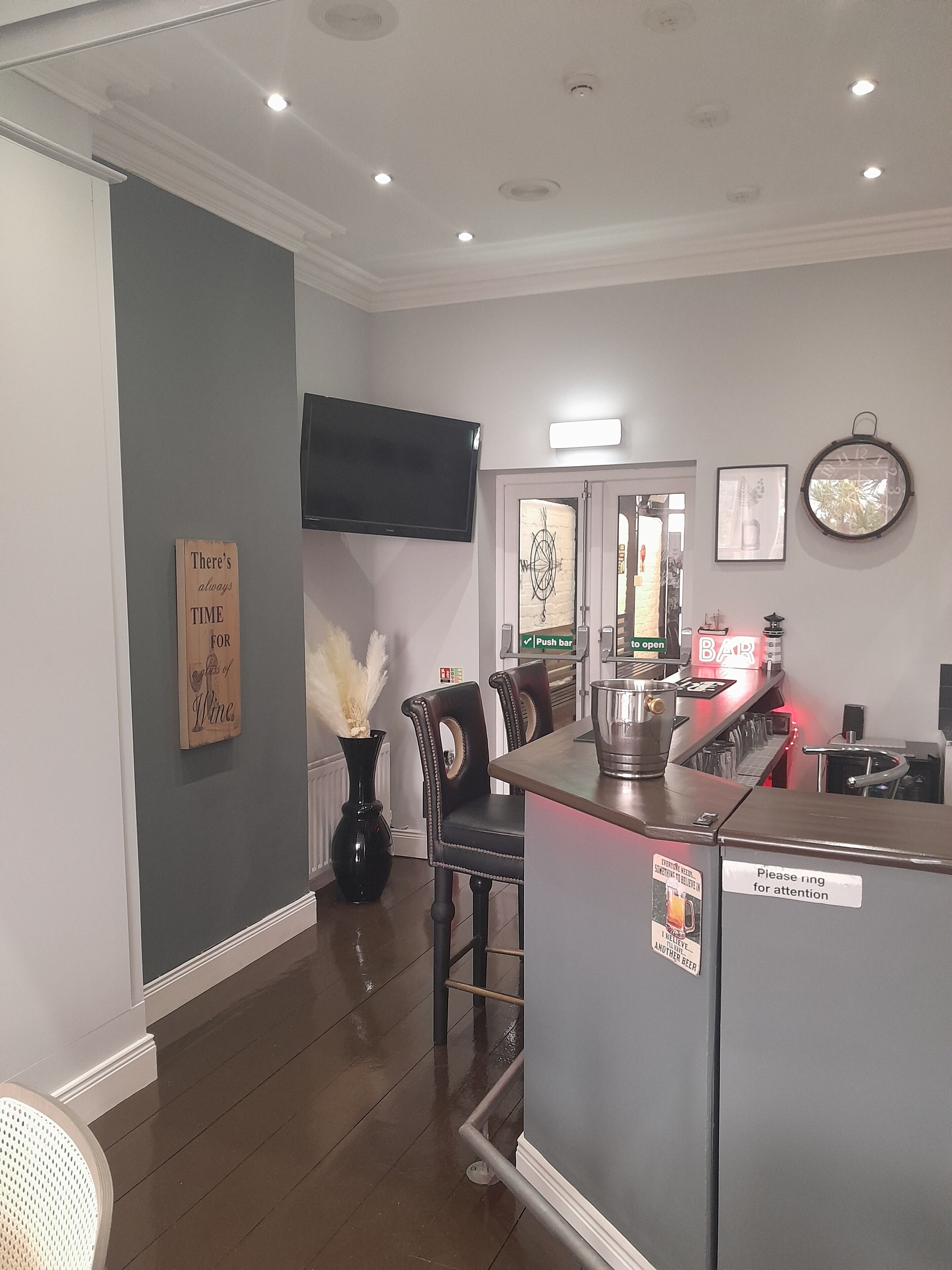 A bar area with a push bar, a television mounted on the wall, and a sign that reads "There's always time for wine."