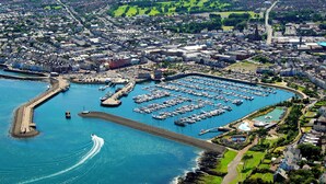 An aerial view of a coastal town with a marina, residential buildings, and a large open park. - Astala Guesthouse (Bangor)