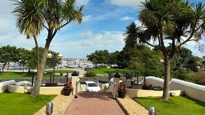 A paved pathway leading to a marina with boats, surrounded by palm trees and a clear sky. - Astala Guesthouse (Bangor)