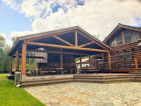 A rustic lodge with a covered patio and stone flooring.