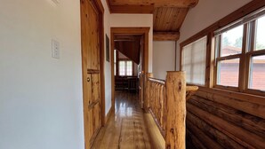 A wooden hallway with a wooden railing, a door, and a window with blinds. - Rustic 1 bedroom, 1 bath, 2 minutes from the West Glacier Park (West Glacier)