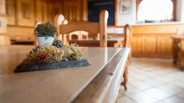 Un tavolo da pranzo in legno con un centrotavola di pigne e verde.