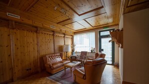 Una stanza con rivestimenti in legno, un divano in pelle, poltrone e un tavolino.