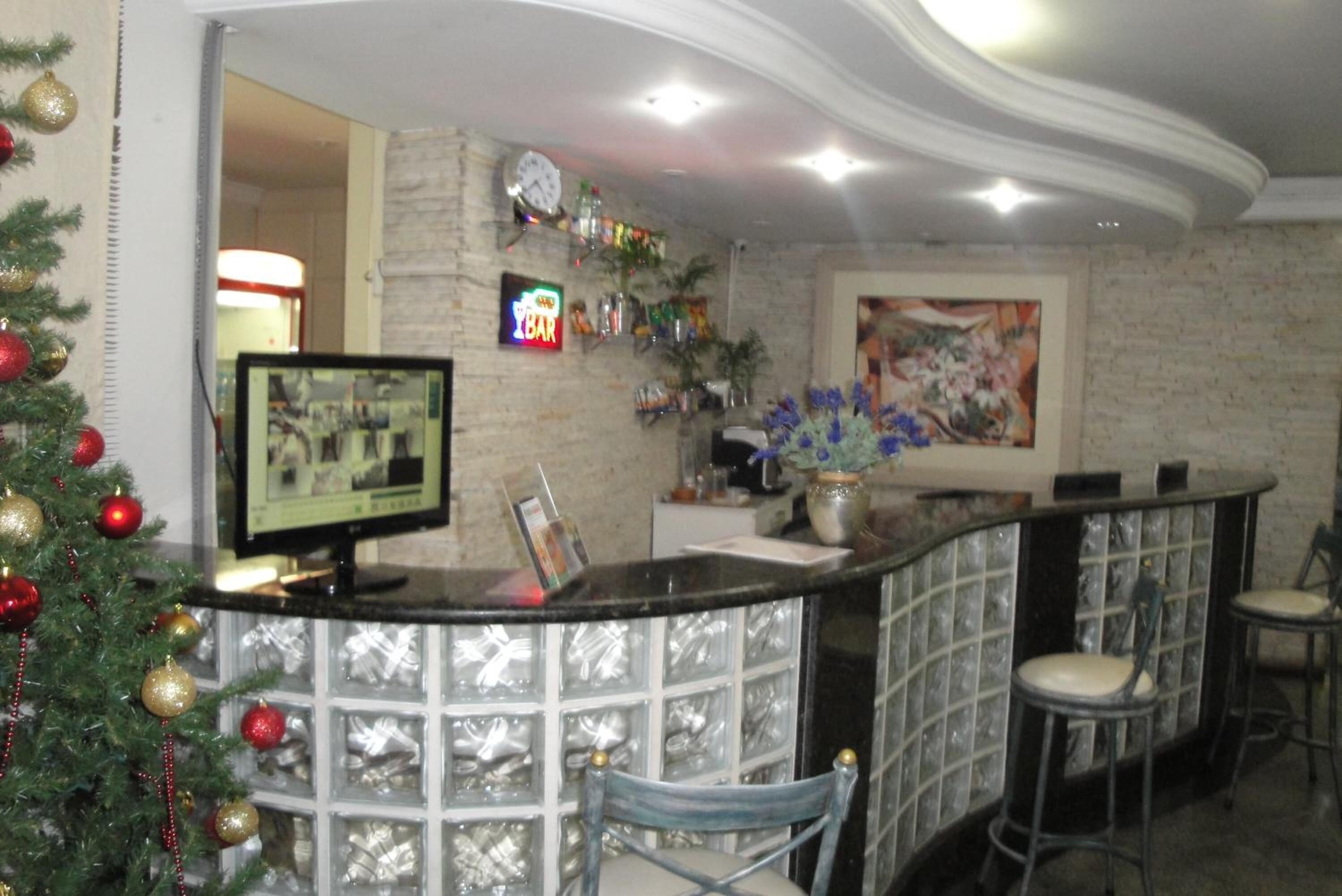 A reception area with a glass partition, a Christmas tree, a clock, and a bar counter with chairs.