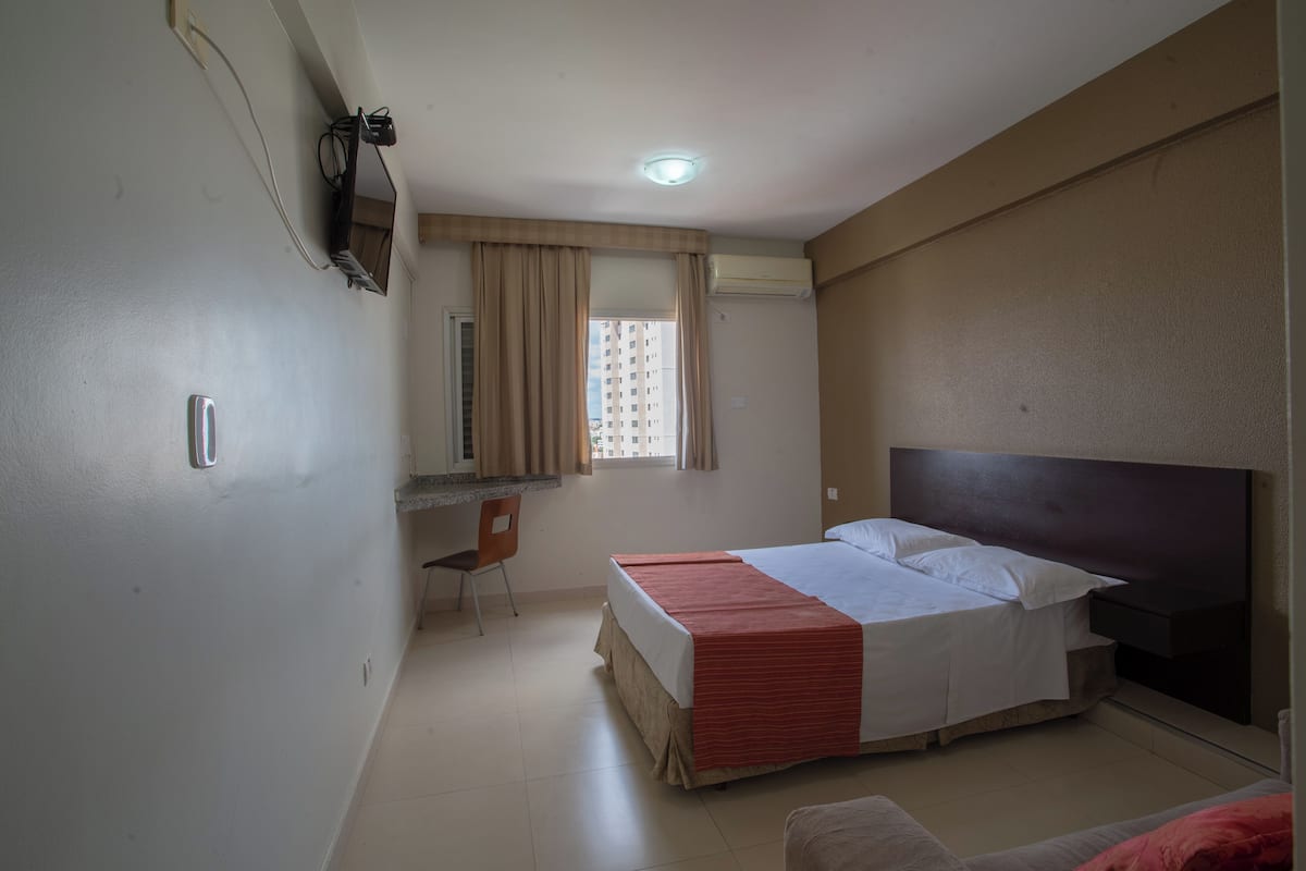 A bedroom with a bed, a desk, and a chair.