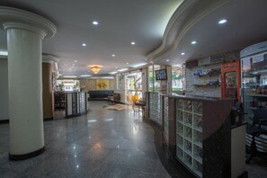 A spacious lobby with a marble floor, a reception desk, and a seating area with a bench and chairs.