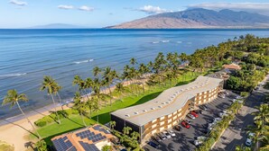 Ein Hotel mit geschwungener Architektur, einem Parkplatz und Blick auf das Meer und die Berge.