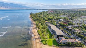 Ein Küstenresort mit Strandzugang, ein großes Gebäude mit gewölbter Dachlinie und Blick auf das Meer und die entfernten Berge.
