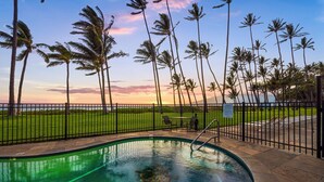 Ein Pool mit Blick auf den Ozean und Palmen bei Sonnenuntergang.