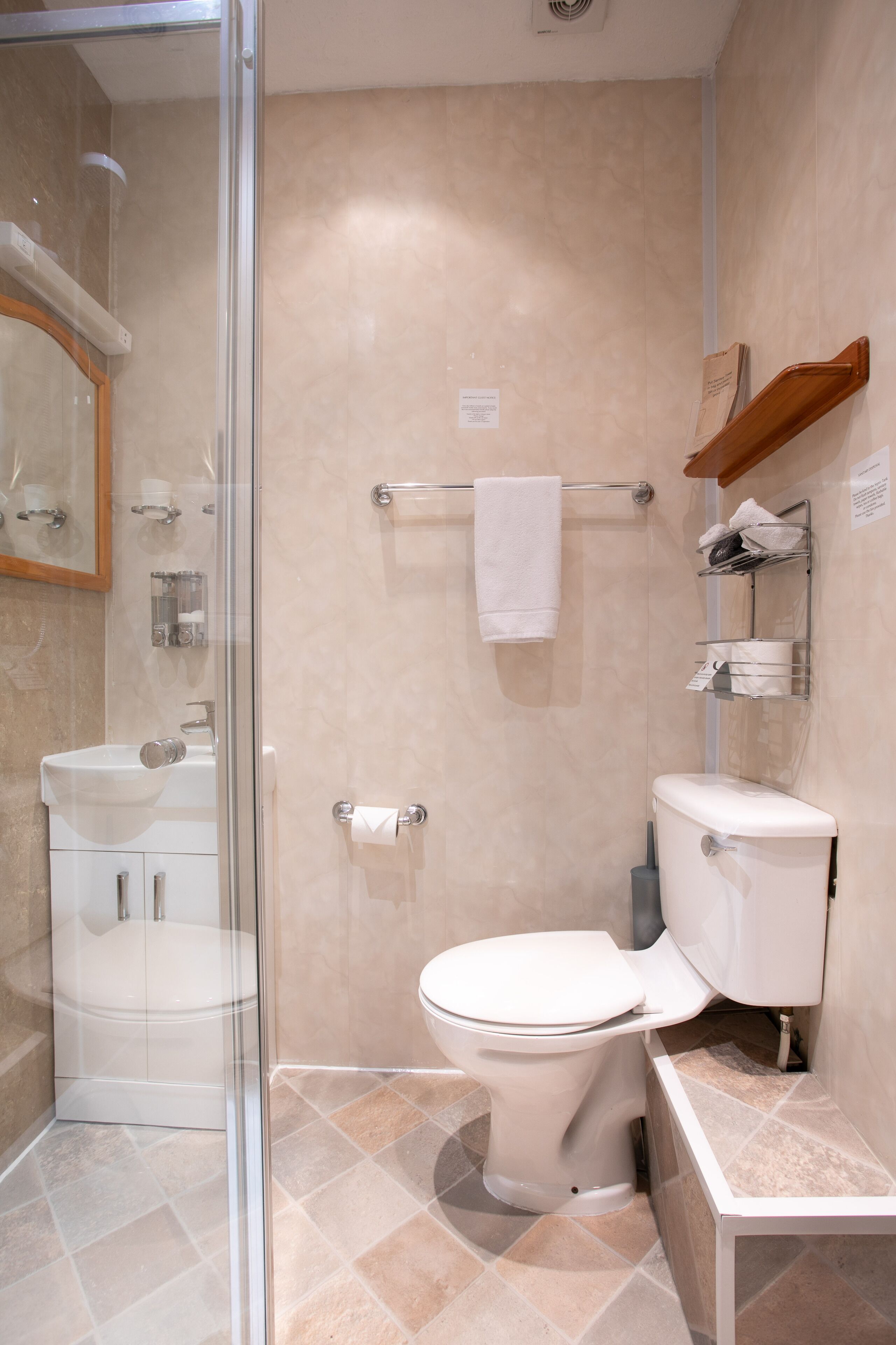 A modern bathroom with a glass-enclosed shower, a white toilet, and a sink.