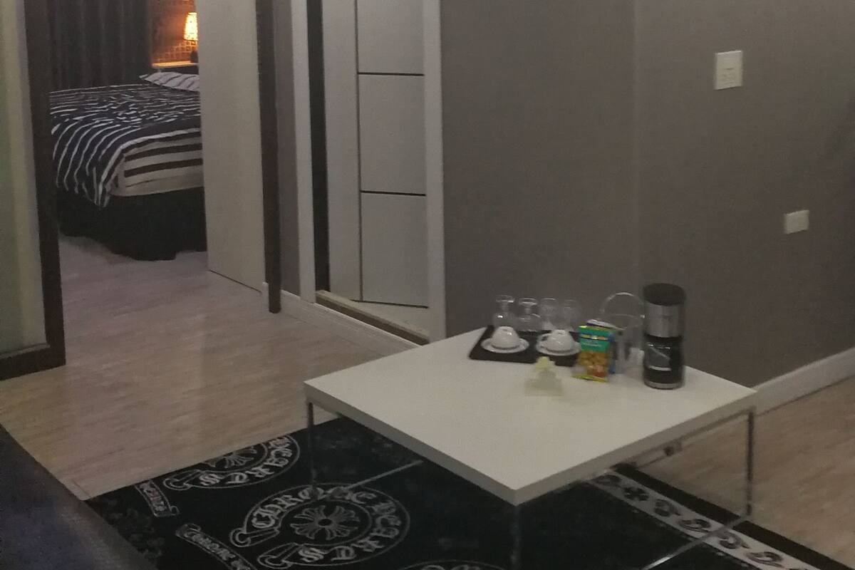 A hotel room with a bed, a small table with a coffee maker, and a chandelier.