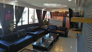 A modern living room with a sofa set, a glass coffee table, and a kitchen area in the background. - Hotler Boutique Apartment (Pattaya)